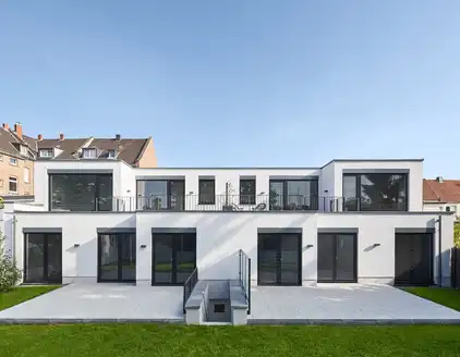 weißes Haus mit dunklen Fenstern und Terrasse