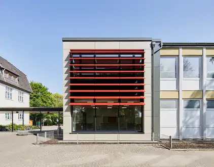 Schule mit roten Lamellen an Fensterfront