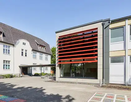 Schule mit roten Lamellen an Fensterfront
