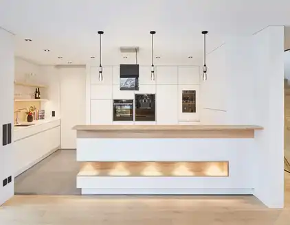 helle weiße Küche mit Küchentheke und Hängelampen