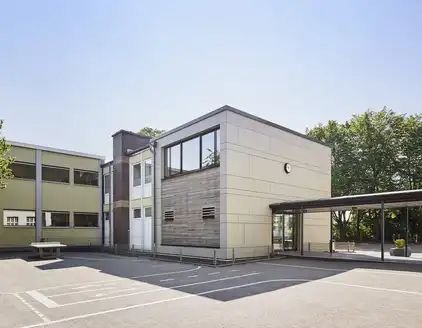 Rückseite von Gebäude mit Holzfassade und Fensterfront im oberen Stockwerk