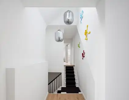 heller Flur mit Blick auf den Treppenaufgang und bunten Figuren an der Wand