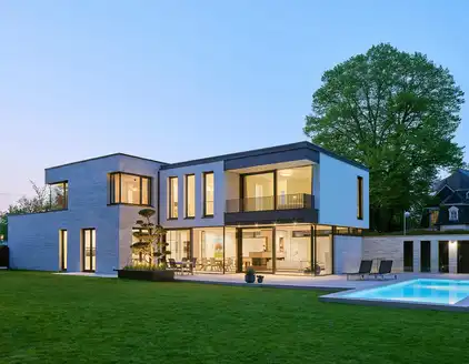 Rückansicht: Haus mit Garten und Pool rechts am Abend
