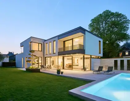 Rückansicht: Haus mit Garten und Pool links am Abend