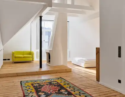 Raum im Dachgeschoss mit Holzboden, Sofa und Bett