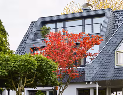 doppelstöckiger Erker an einem dunkel blauen Spitzdach 