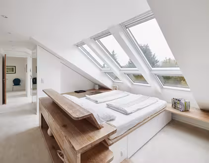 Schlafzimmer mit Bett in der Mitte und Blick auf Dachfensterfront