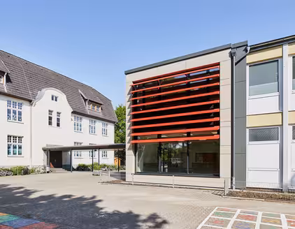 Schule mit roten Lamellen an Fensterfront