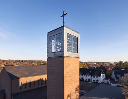 Glockenturm mit Glaswürfel oben, großes Kreuz als Spitze