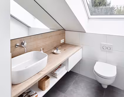 Badezimmer in weiß mit Holzanrichte links, Toilette rechts und Dachfenster