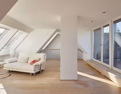 Sofa in einem Raum mit Dachschräge und Fensterfront an beiden Seiten