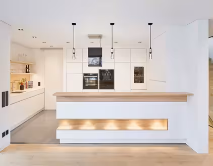 helle weiße Küche mit Küchentheke und Hängelampen