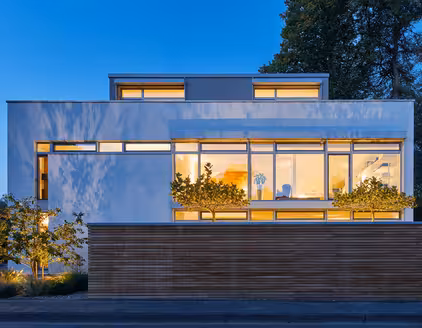 Gebäude, teilweise mit Holzfassade, erleuchtete Fenster