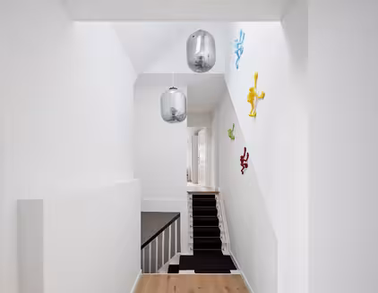 heller Flur mit Blick auf den Treppenaufgang und bunten Figuren an der Wand