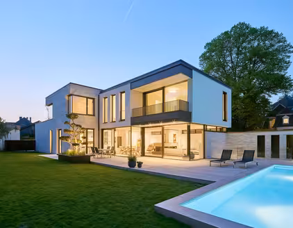 Rückansicht: Haus mit Garten und Pool links am Abend