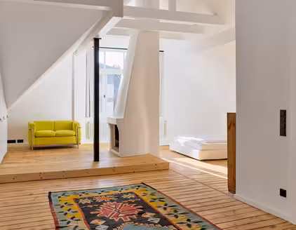 Raum im Dachgeschoss mit Holzboden, Sofa und Bett