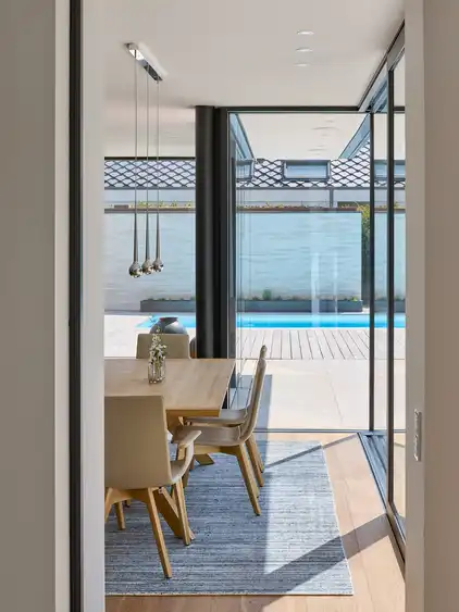 Tischgarnitur links, vorne und rechts Fensterfront mit Blick auf den Pool