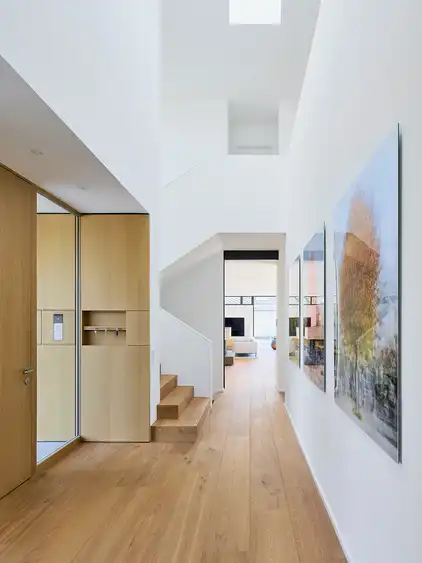 heller Flur mit großen Bildern, Parkett, Treppe und Eingang links