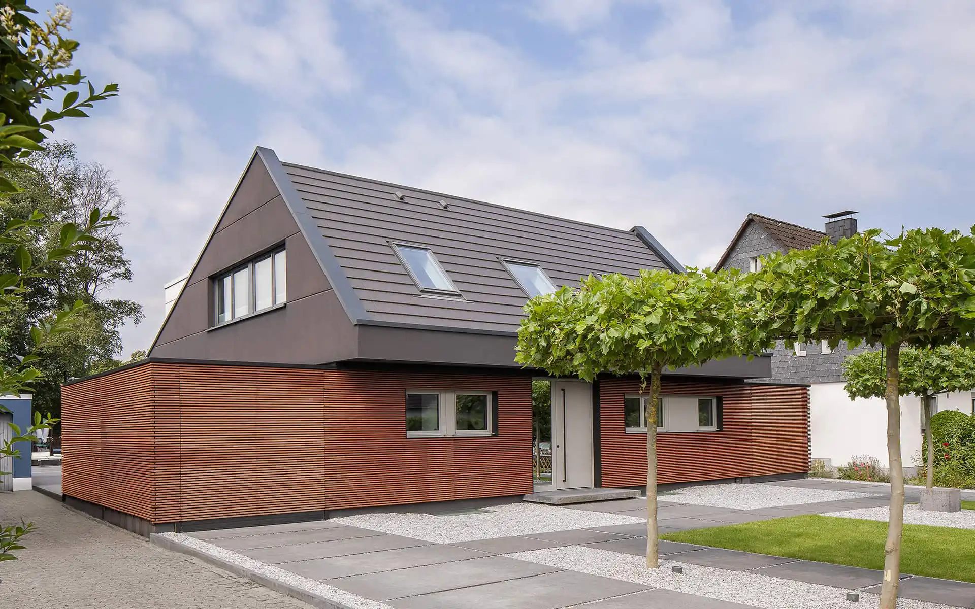 zweistöckiges Haus mit rötlicher Holzfassade und grauem Spitzdach