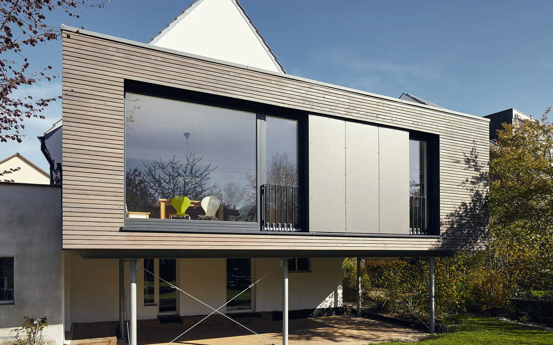 Haus mit Holzfasssade und Glasfront auf Stützen 