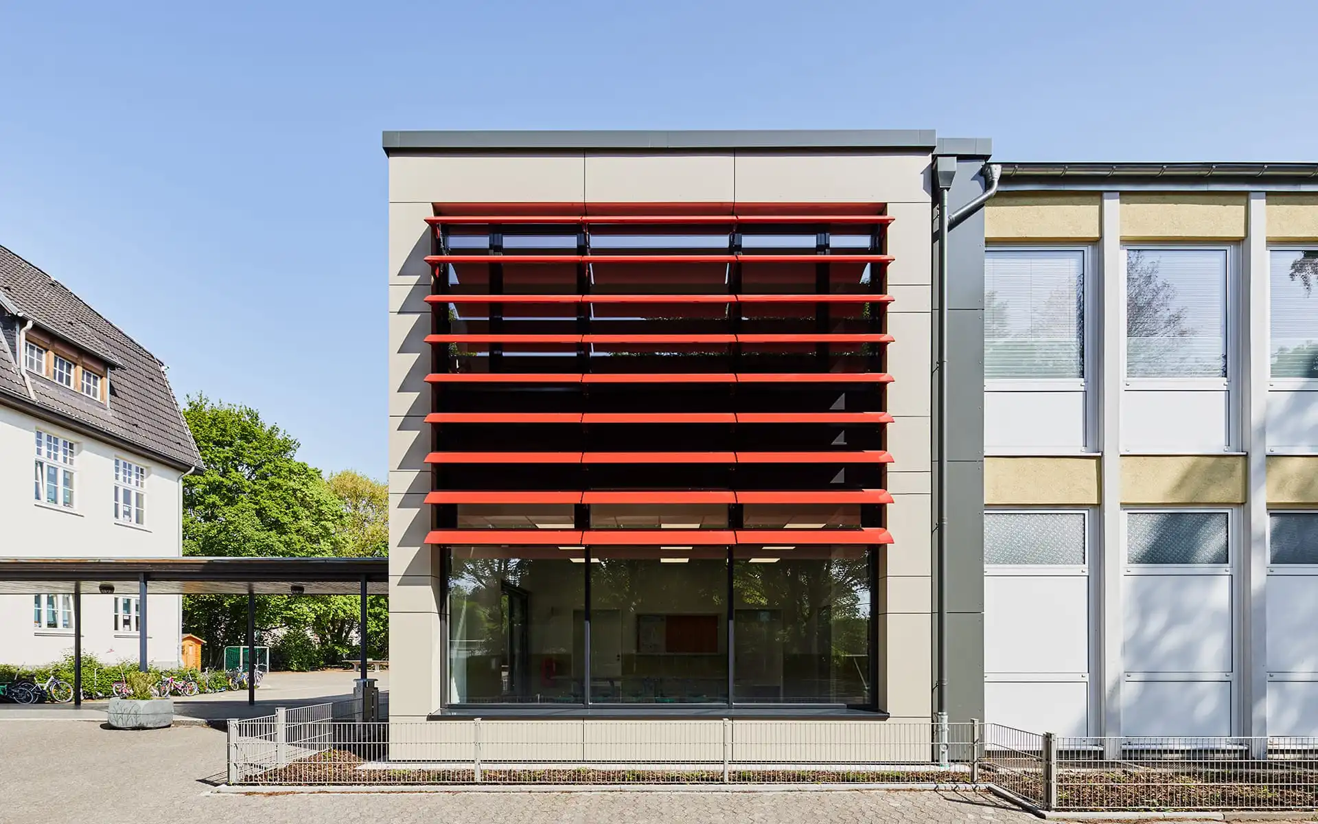 Schule mit roten Lamellen an Fensterfront