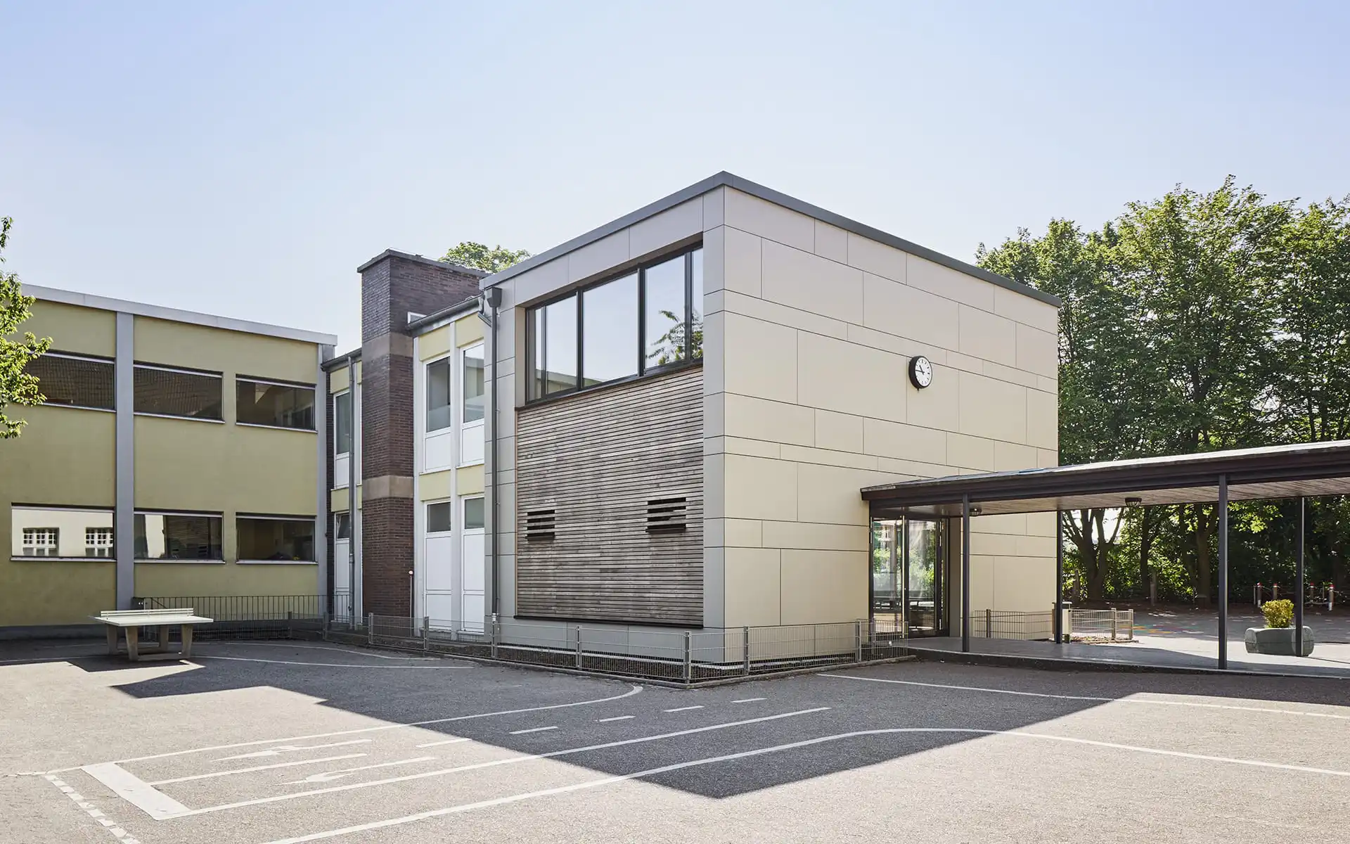 Rückseite von Gebäude mit Holzfassade und Fensterfront im oberen Stockwerk