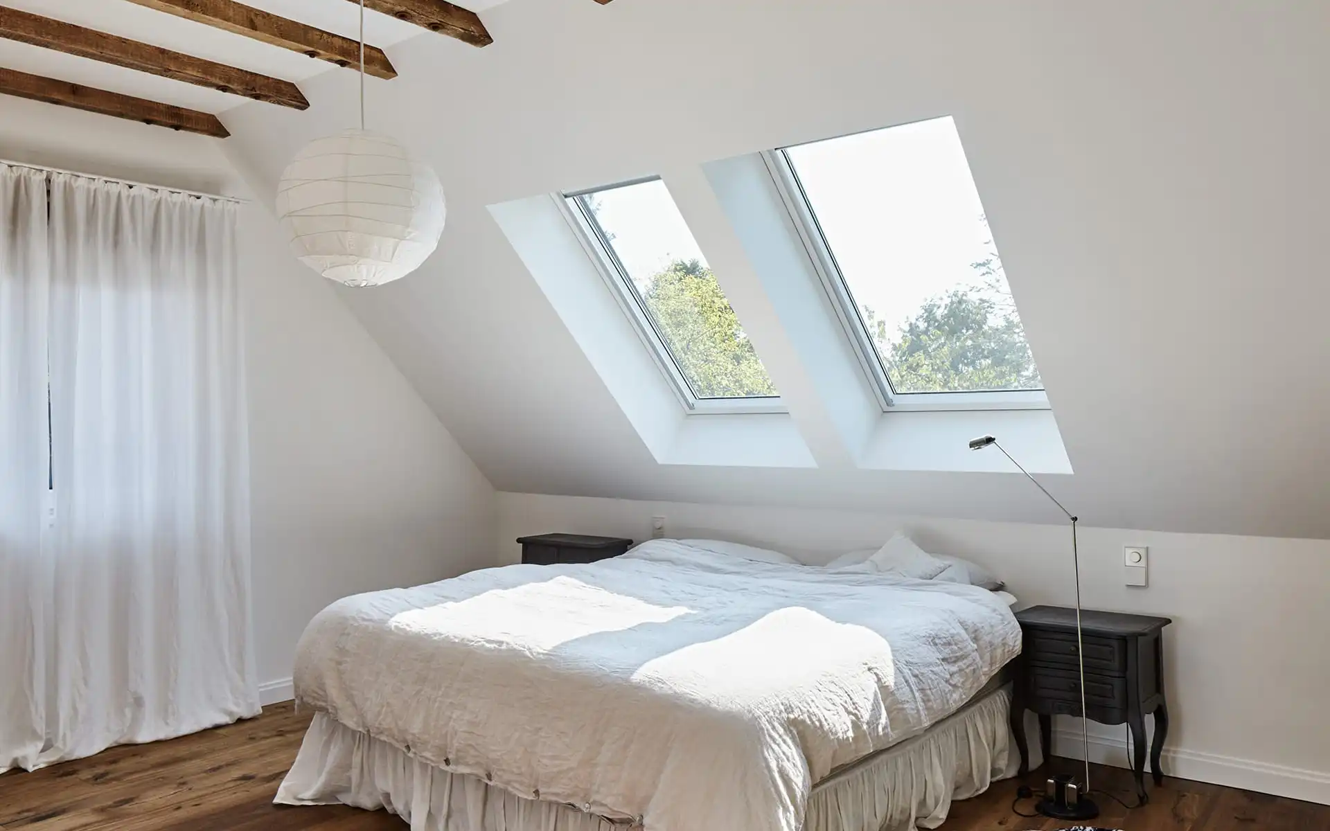 Schlafzimmer mit Holzdeckenbalcken, Doppelbett in der Mitte, Blich auf Dachfenster