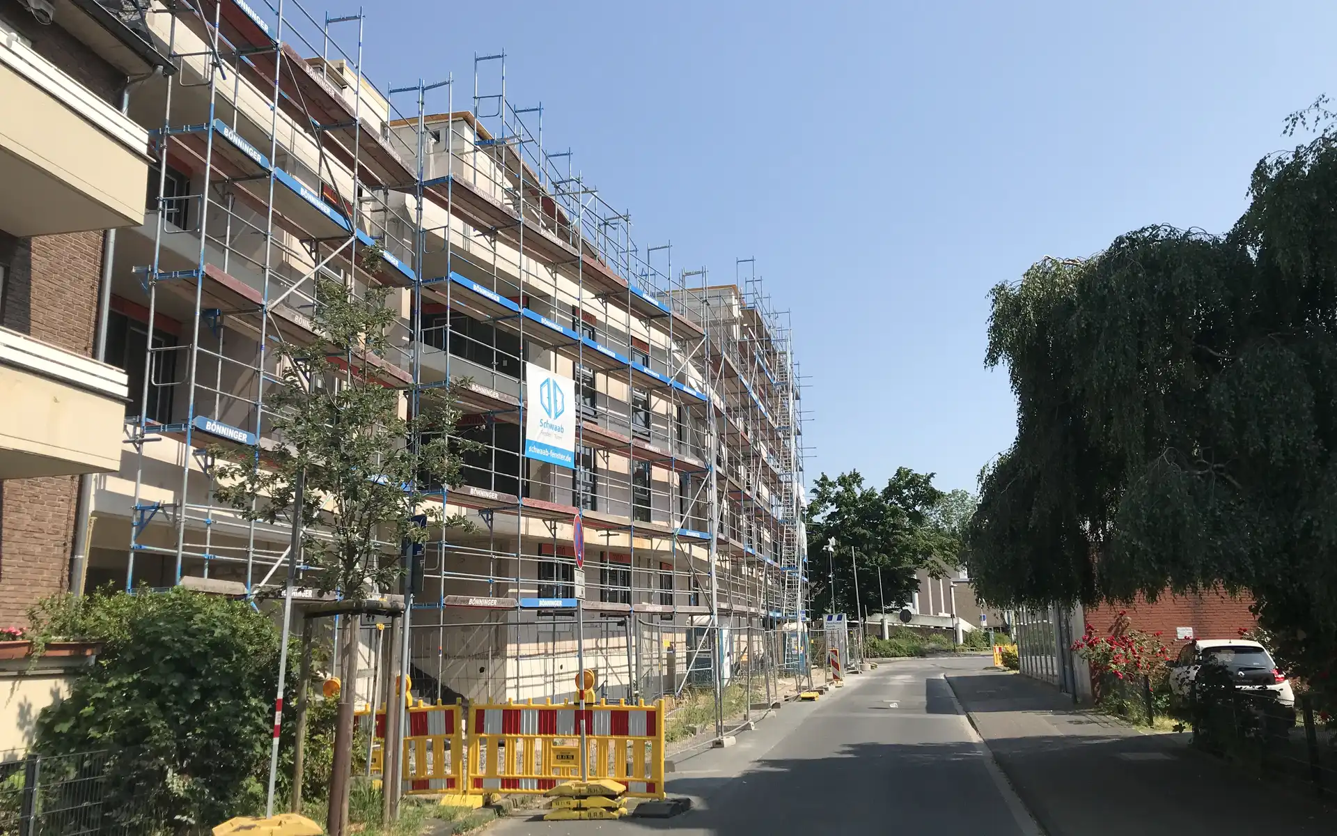 mehrstöckiges unfertiges Gebäude mit Bauzaun, Blick von der Straße aus