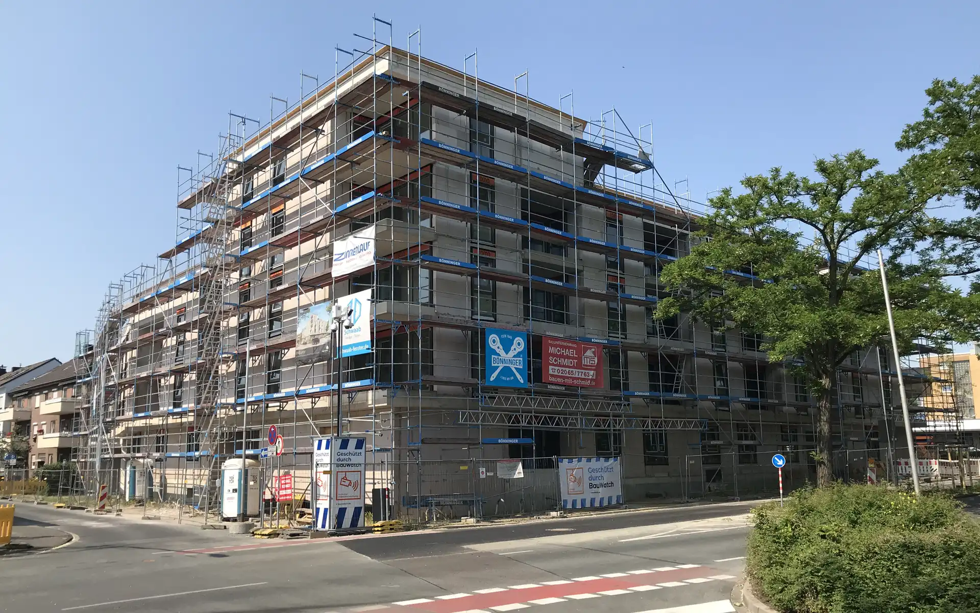 mehrstöckiges unfertiges Gebäude mit Bauzaun, Blick von der Straße aus