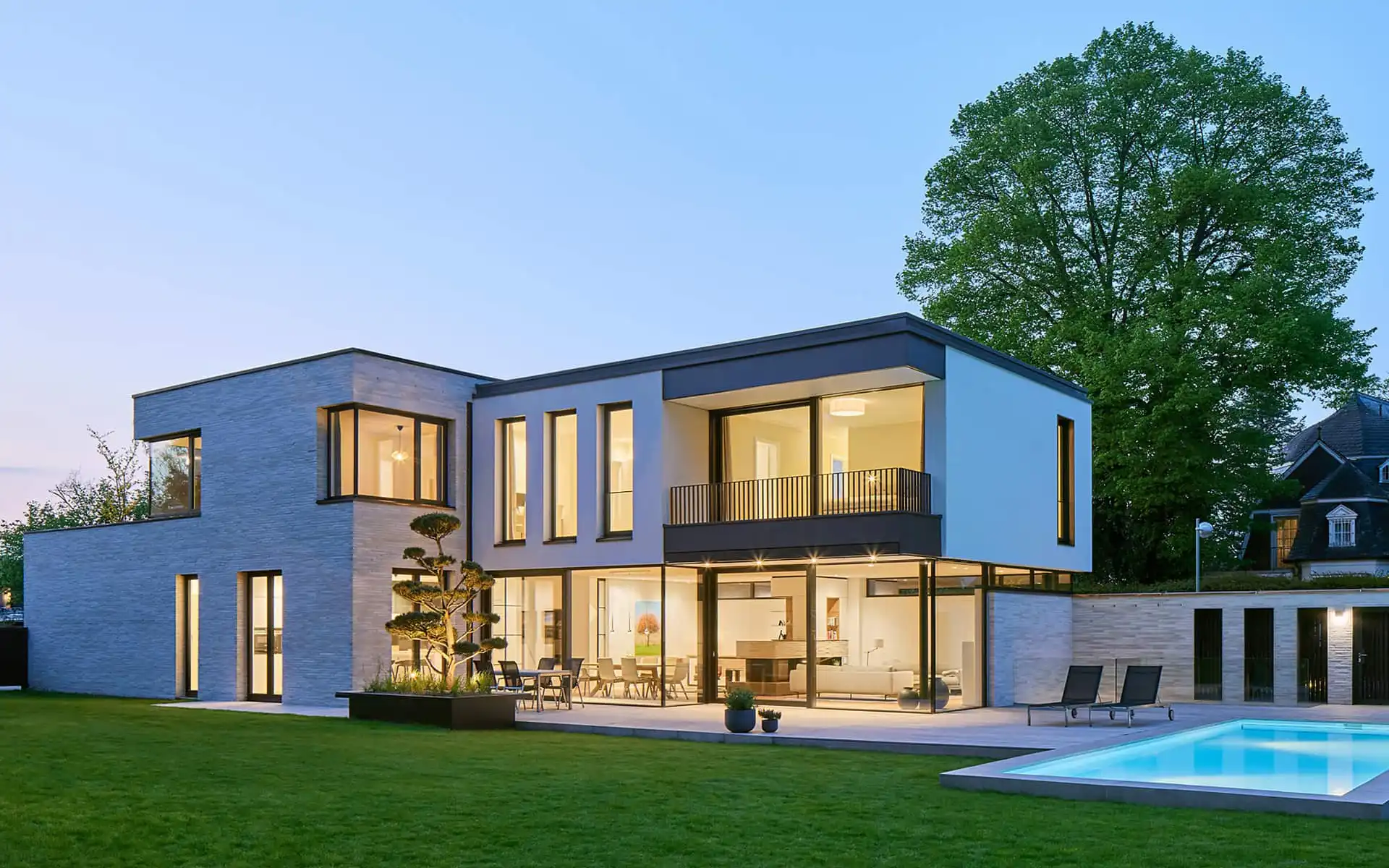 Rückansicht: Haus mit Garten und Pool rechts am Abend