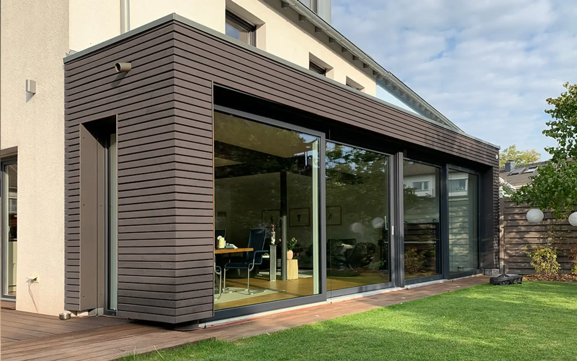 Vorbau mit Holzfassade und Fensterfront zum Garten hin