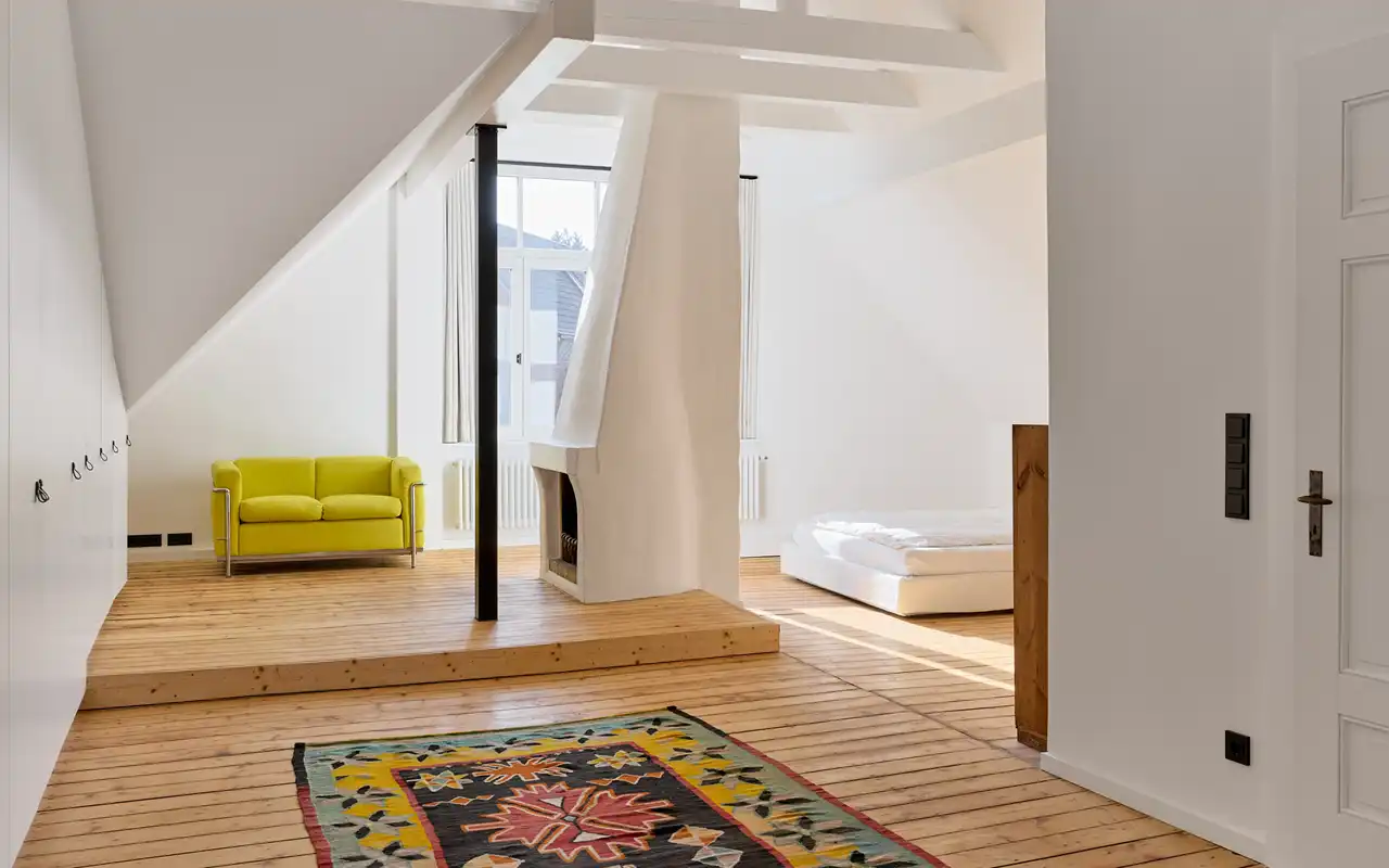 Raum im Dachgeschoss mit Holzboden, Sofa und Bett