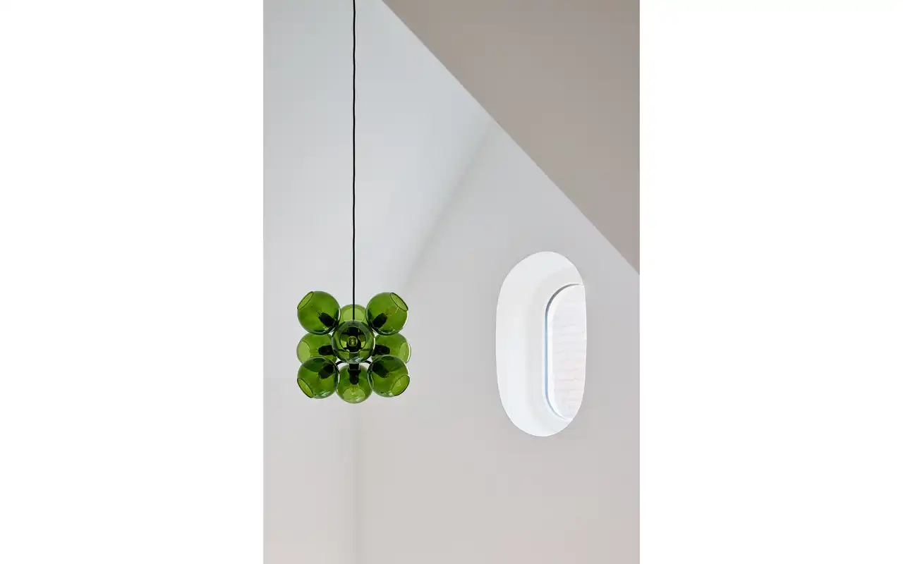 Grüne Designlampe vor einer weißen Wand mit Fenster