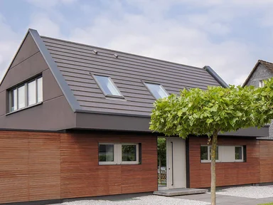 zweistöckiges Haus mit rötlicher Holzfassade und grauem Spitzdach