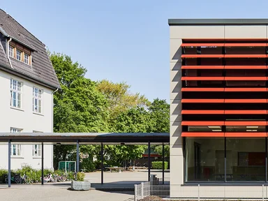 Schule mit roten Lamellen an Fensterfront