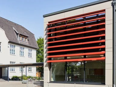 Schule mit roten Lamellen an Fensterfront