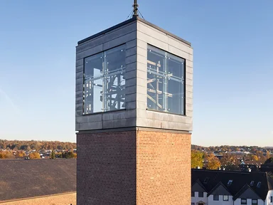 Glockenturm mit Glaswürfel oben, großes Kreuz als Spitze