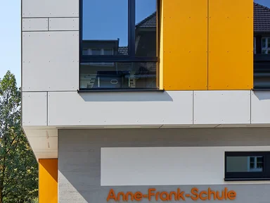 graues Gebüude mit Aufstockung, gelbe Akzente in Fassade