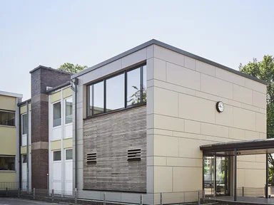 Rückseite von Gebäude mit Holzfassade und Fensterfront im oberen Stockwerk