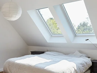 Schlafzimmer mit Holzdeckenbalcken, Doppelbett in der Mitte, Blich auf Dachfenster