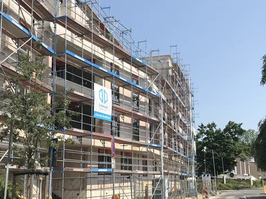 mehrstöckiges unfertiges Gebäude mit Bauzaun, Blick von der Straße aus