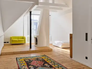 Raum im Dachgeschoss mit Holzboden, Sofa und Bett