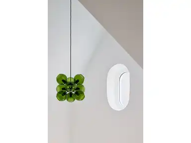Grüne Designlampe vor einer weißen Wand mit Fenster