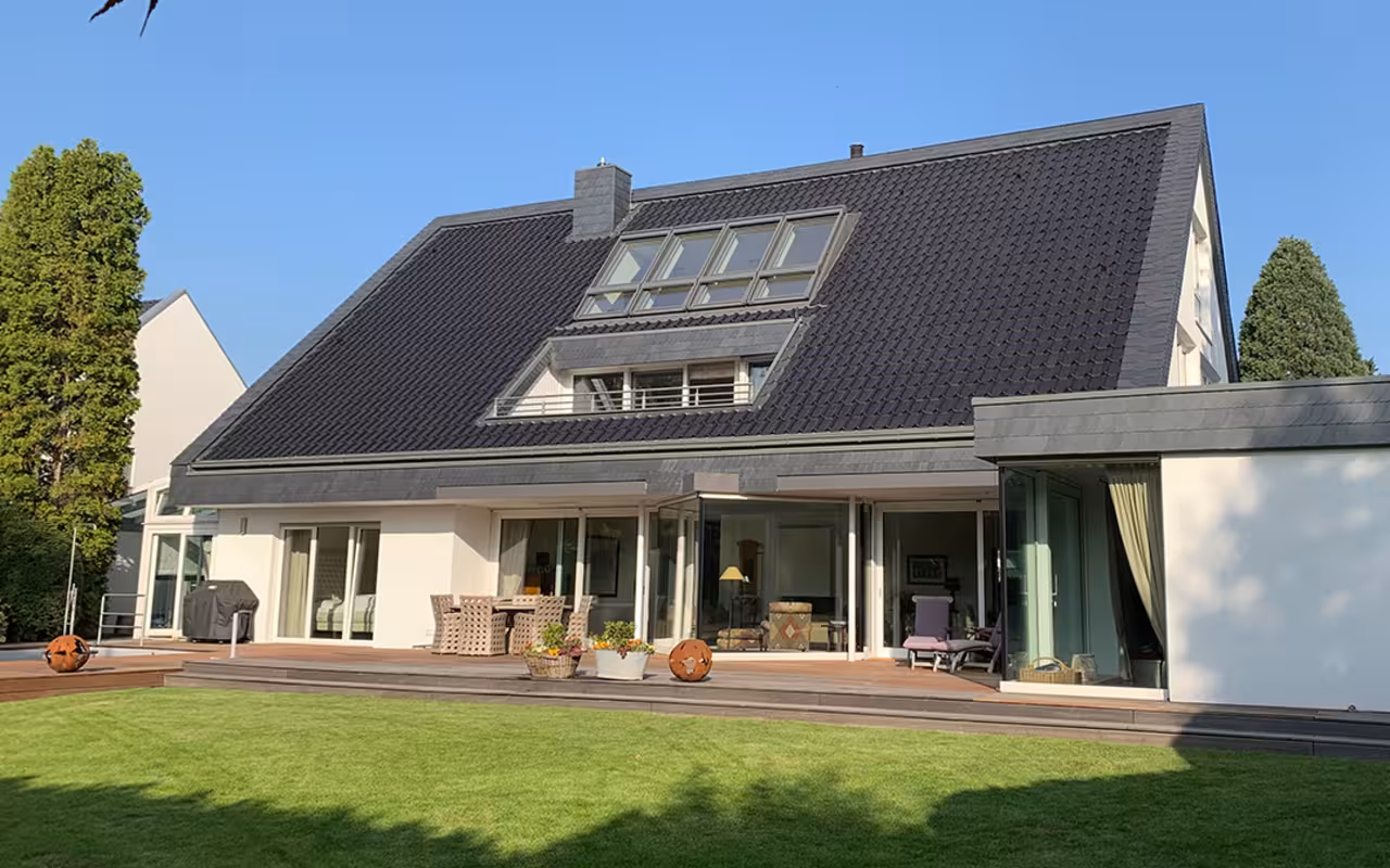 Dreistöckiges weißes Haus mit dunklem Spitzdach über zwei Etagen