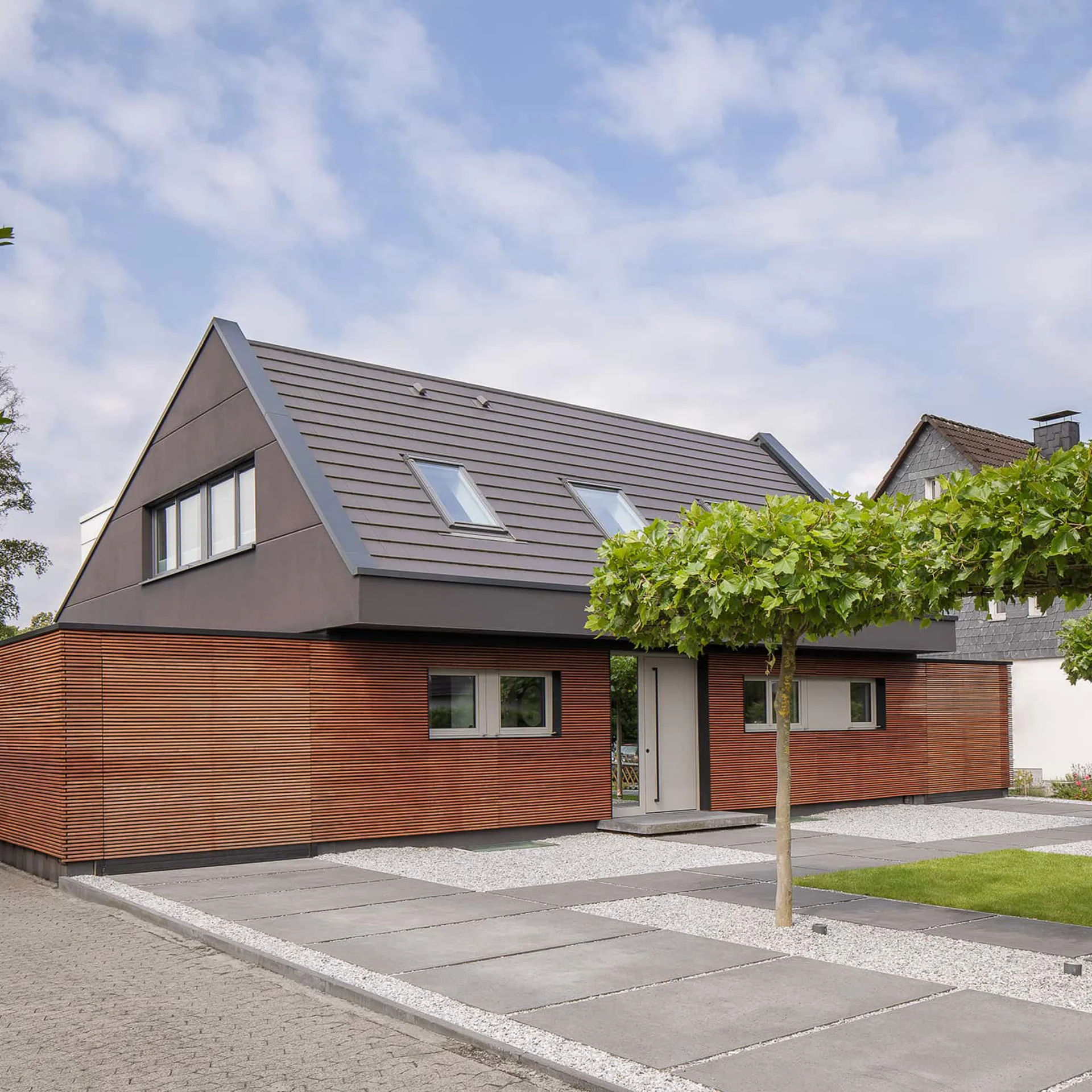 zweistöckiges Haus mit rötlicher Holzfassade und grauem Spitzdach