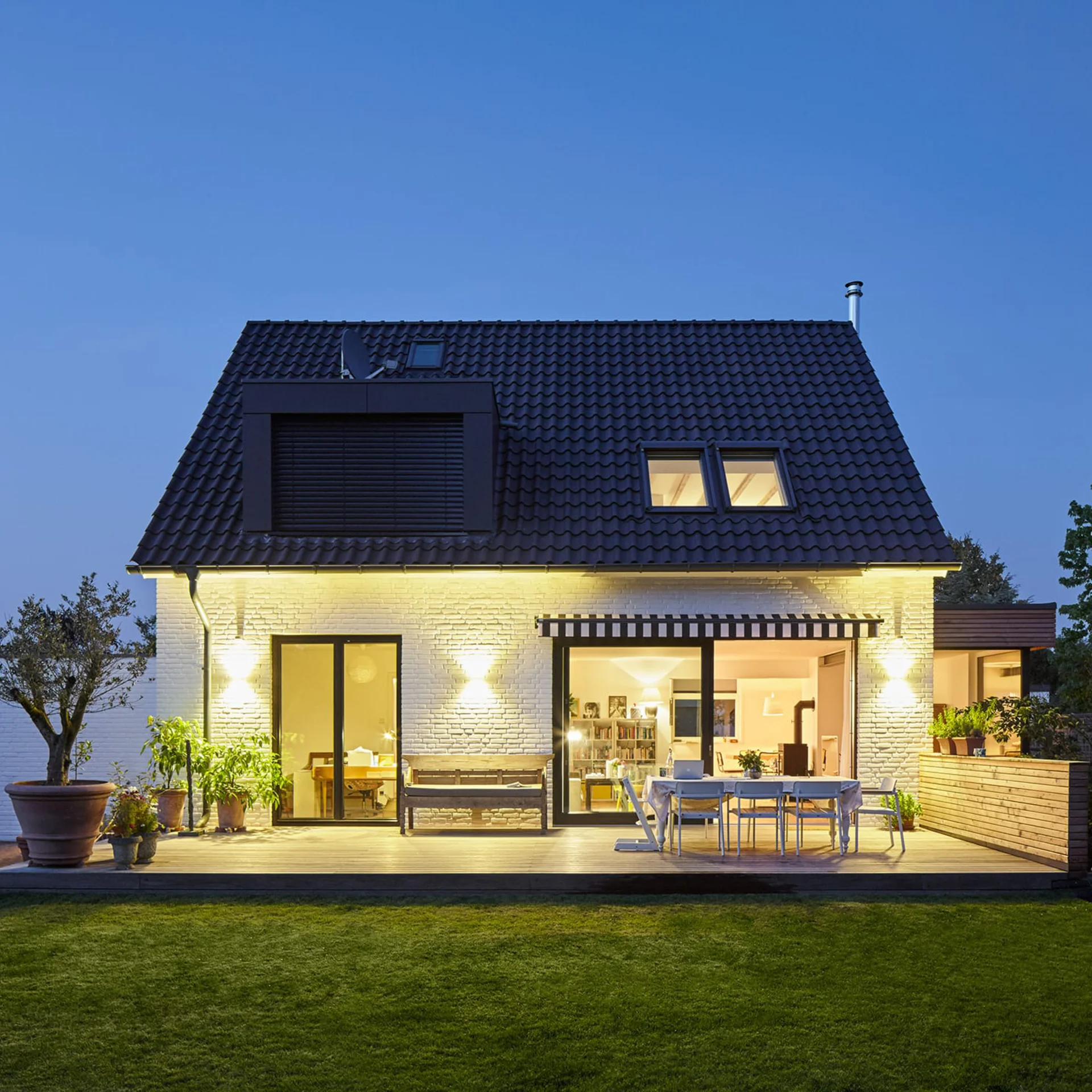 Zweistöckiges weißes Haus mit dunkelblauem Spitzdach und Garten