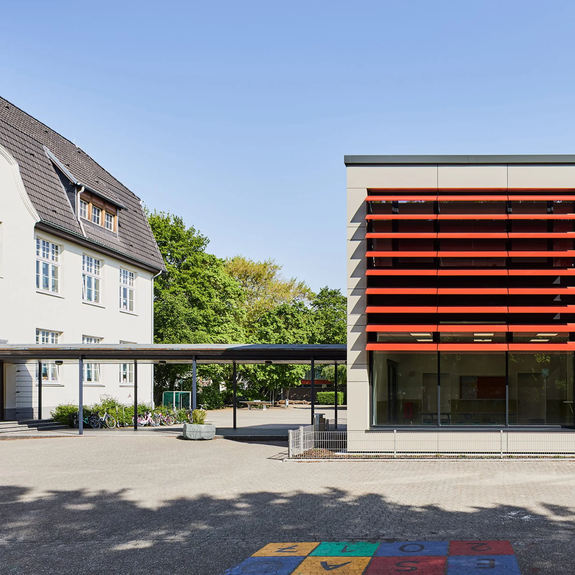 Schule mit roten Lamellen an Fensterfront