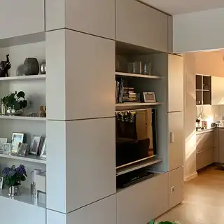 Raum mit Einbauregalen links, Küche rechts