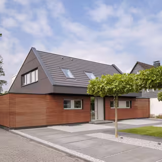 zweistöckiges Haus mit rötlicher Holzfassade und grauem Spitzdach